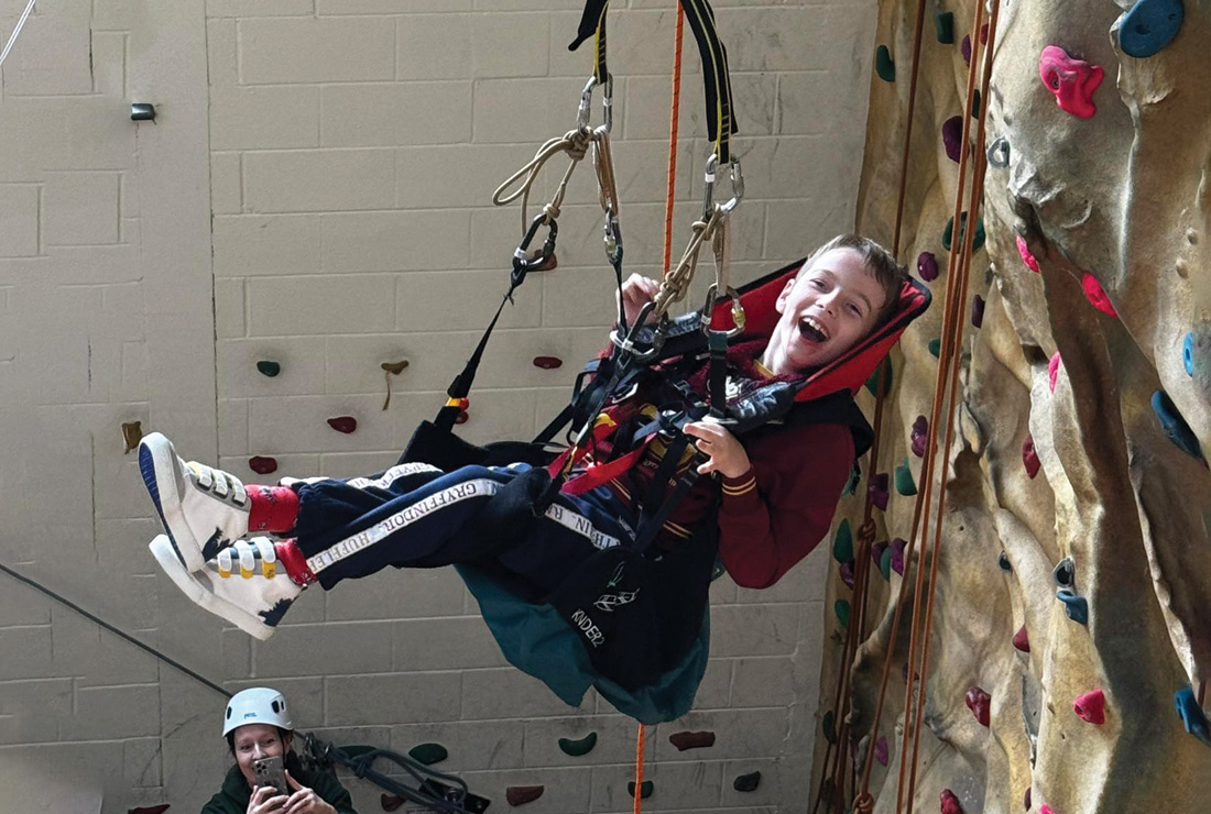 Boy with MLD on climbing wall at Bendrigg Trust